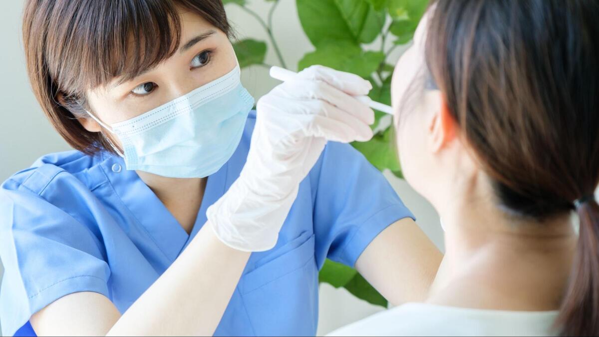 歯科衛生士がマスクと手袋を着用し、器具を使って患者の口内を診察・検査している様子