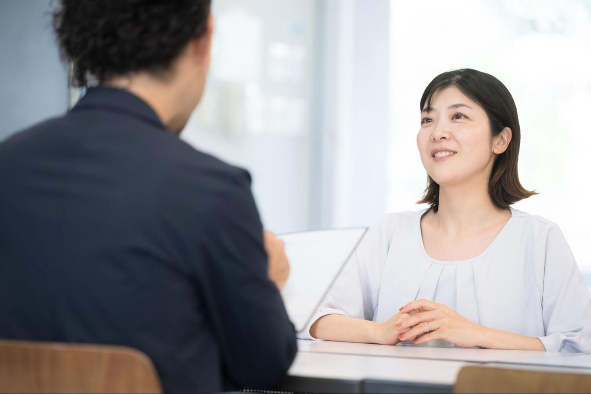 スーツ姿の男性とテーブル越しに対面し、穏やかな表情で話を聞いている女性